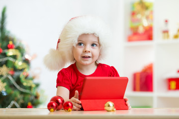 toddler girl in christmas hat with tablet pc
