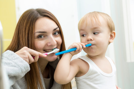 mother and kid son brushing teeth in bathroom