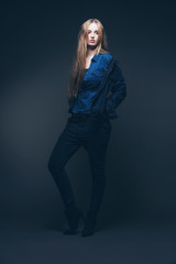 Woman jeans winter fashion. Long blonde hair. Studio shot agains