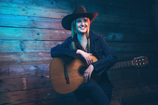 Cowgirl Country Singer With Acoustic Guitar. Wearing Blue Jeans