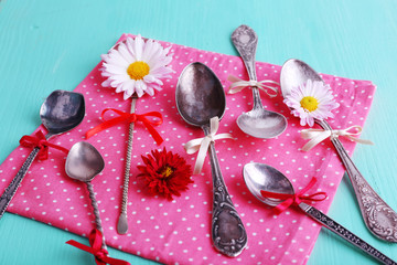 Obraz na płótnie Canvas Metal spoons on pink polka dot napkin on wooden background