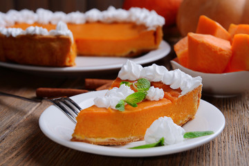Piece of homemade pumpkin pie on plate on wooden background