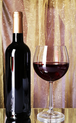 Red wine glass and bottle of wine on bright background