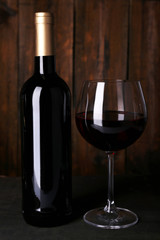Red wine glass and bottle of wine on wooden background