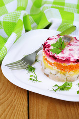 Russian herring salad on plate on wooden table background