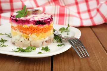 Russian herring salad on plate on wooden table background
