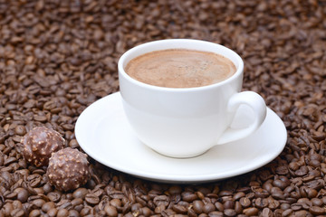 cup of coffee and candies on a coffee beans background