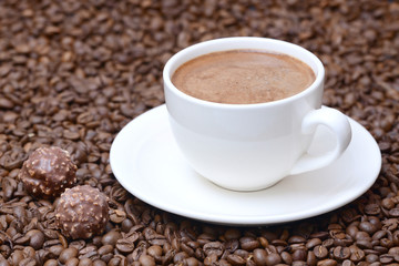 cup of coffee and candies on a coffee beans background
