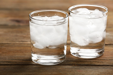 Glasses with ice cubes on wooden table