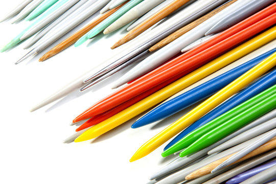 Tips of Multicolored Plastic Knitting Needles on White