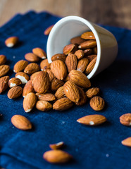 scatter nuts almonds in a white bowl on blue napkin