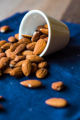 scatter nuts almonds in a white bowl on blue napkin