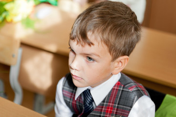 Pupil in uniform sitting at desk in school classroom