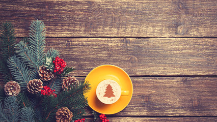 Hot cappuccino with christmas tree shape on a wooden table near