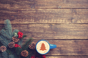 Hot cappuccino with christmas tree shape on a wooden table near