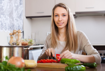 Obraz na płótnie Canvas woman slicing red pepper in kitchen