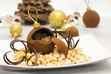 chocolate bauble with glazed chestnut inside against christmas b