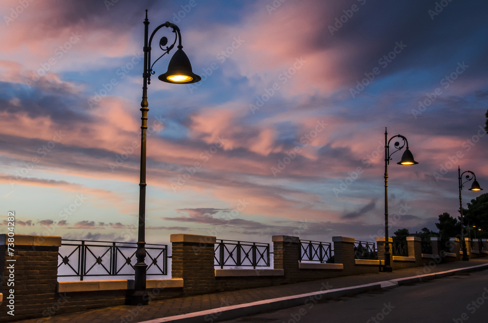 Wall mural strada con lampioni accesi al tramonto