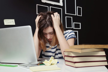 Young woman feeling stressed in front of laptop.