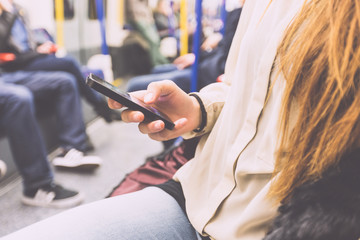 Young Woman Using Smart Phone in London Tube - obrazy, fototapety, plakaty