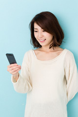 Fototapeta premium attractive asian woman using smart phone on blue background