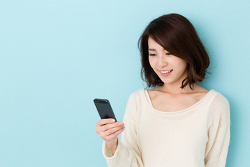 Fototapeta premium attractive asian woman using smart phone on blue background