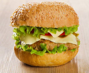 Hamburger with  vegetables on a wooden table.