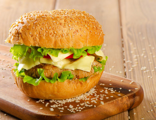Hamburger with  vegetables on  wooden table.