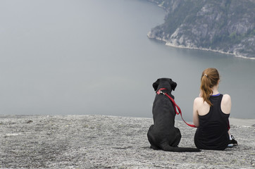 woman with her dog sitting on a cliff