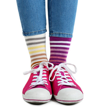 Female Legs In Colorful Socks And Sneakers Isolated On White