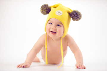 Baby in yellow winter hat lying on the floor