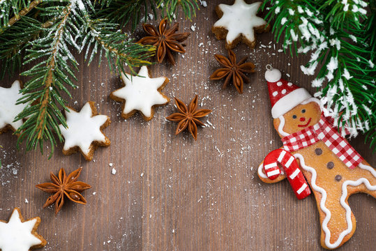 wooden background with fir branches, cookies and gingerbread man