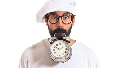 Crazy chef holding a clock over white background