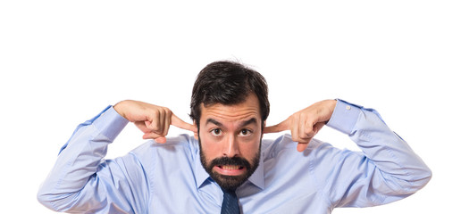 Businessman covering his ears over white background
