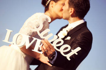 Bride and groom posing with Sweet Love letters