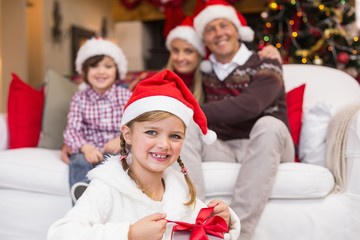 Little girl opening a gift with her family behind