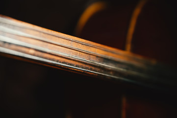 fretboard of old shabby cello on a black backgrounds