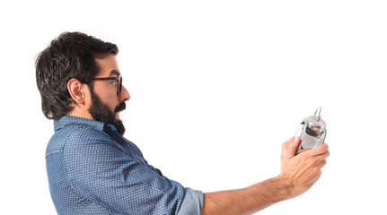 Surprised young hipster man holding a clock