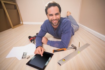 Casual man lying on floor using tablet pc for DIY instructions