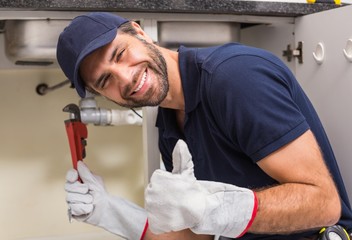 Plumber smiling at the camera fixing under the sink