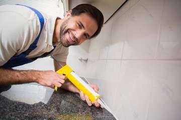 Plumber putting filling in between tiles