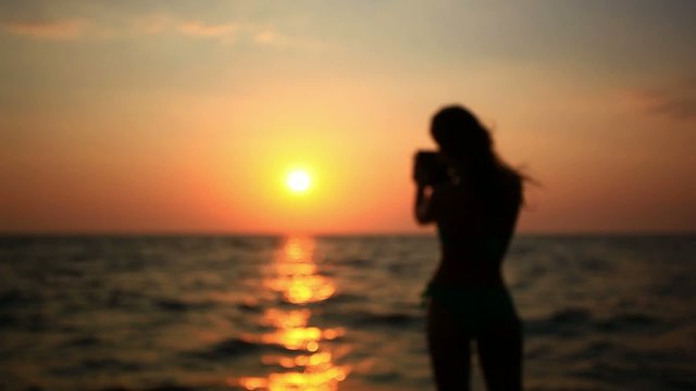 Silhouette of young woman takes a picture from phone on the
