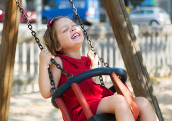 Laughing girl in red dres on  swing