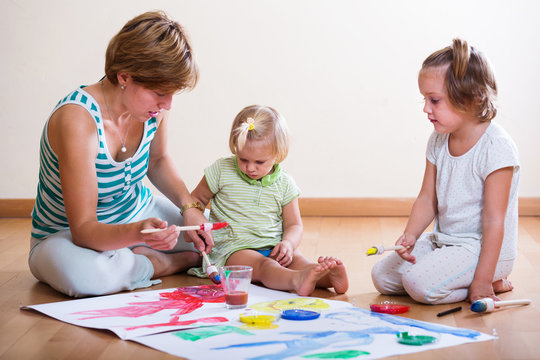 Mother and siblings painting with paints