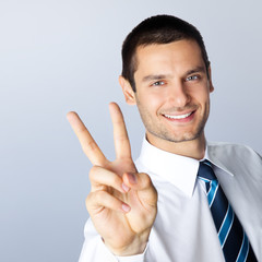 Businessman showing two fingers, against grey