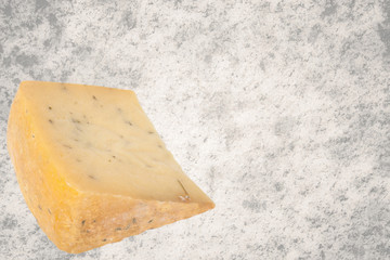 triangular piece of cheese with herbs isolated on granite backgr
