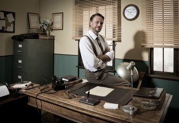 Smiling vintage businessman sitting on desk