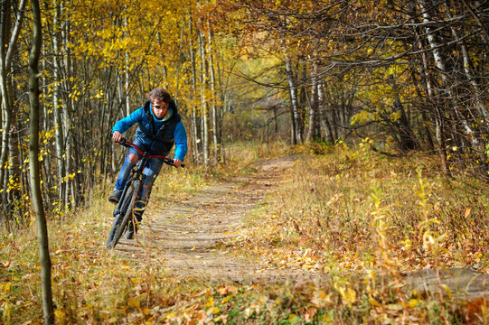 Extreme cyclist riding on mountain bike in autumn forest