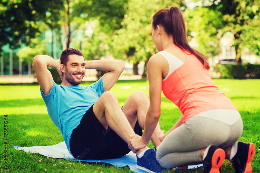 Wall mural smiling man doing exercises on mat outdoors