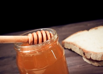 honey jar on wood table with wooden dipper inside